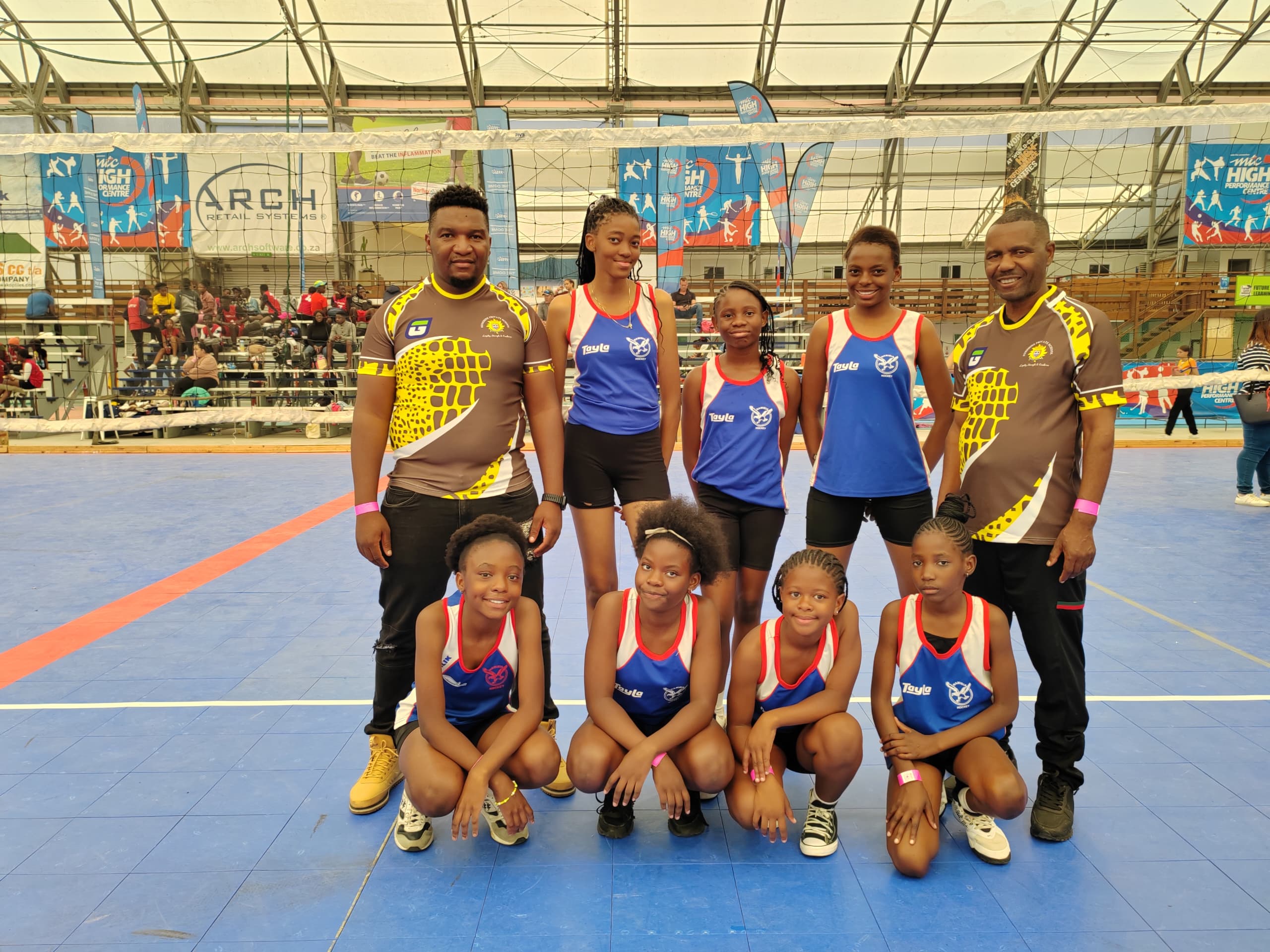 Young volleyball team posing with their coaches