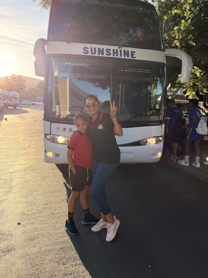 A Sunshine staff member and learner standing in front of a school bus